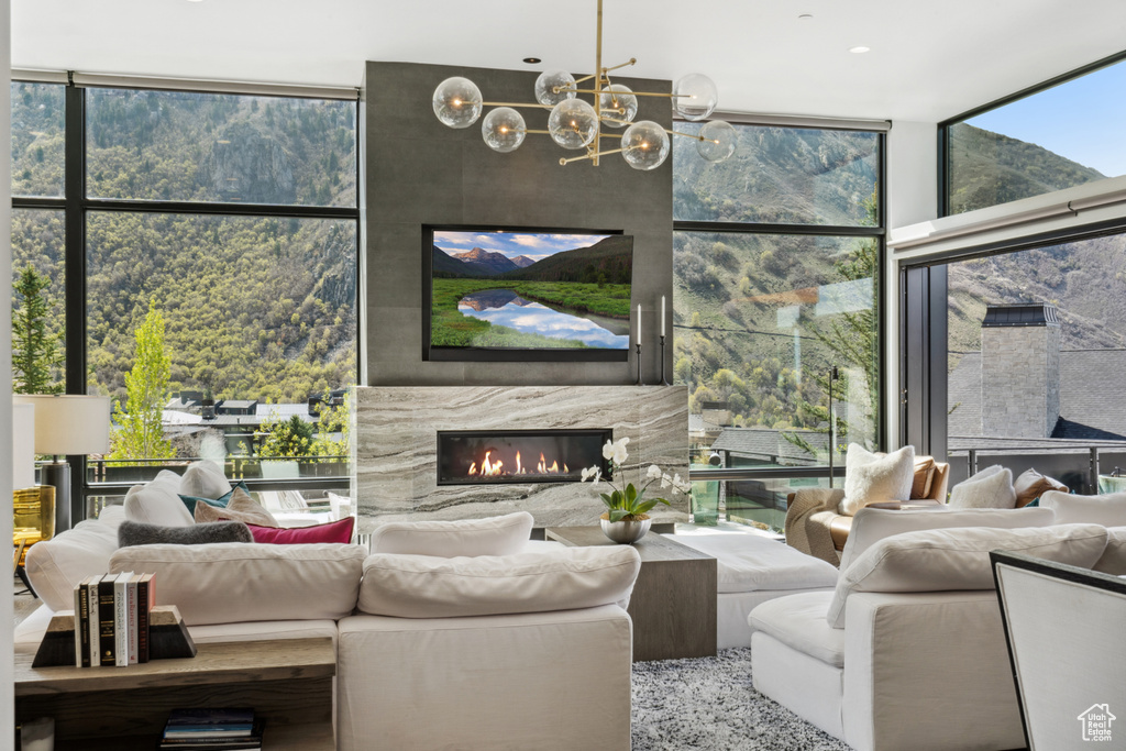 Living room featuring floor to ceiling windows, plenty of natural light, a chandelier, and a high end fireplace