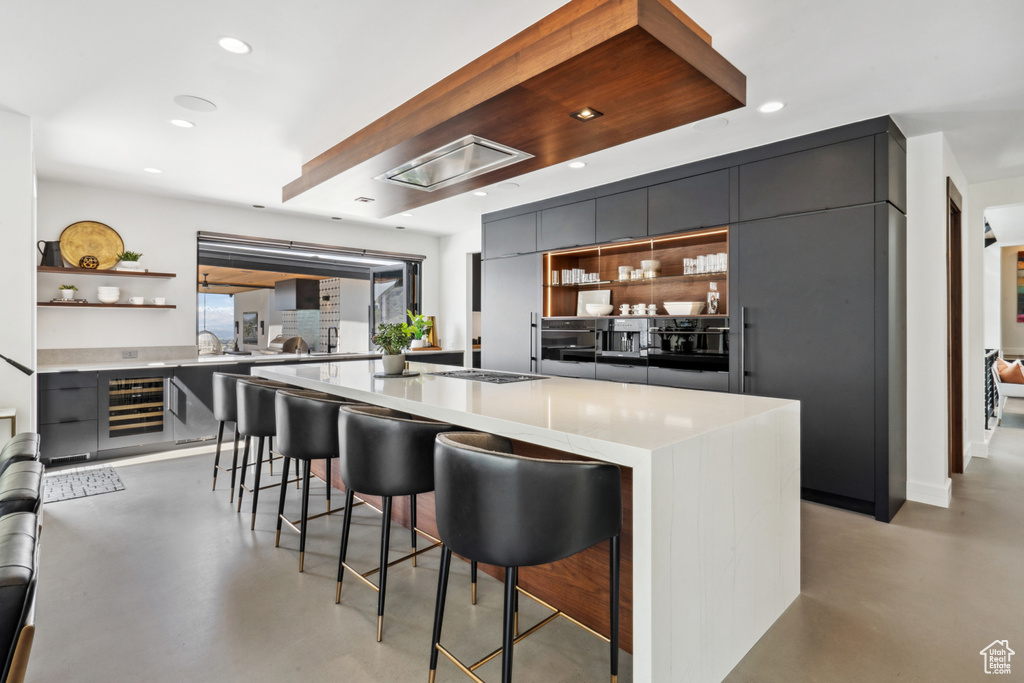 Kitchen with a center island, oven, a breakfast bar, beverage cooler, and gray cabinets