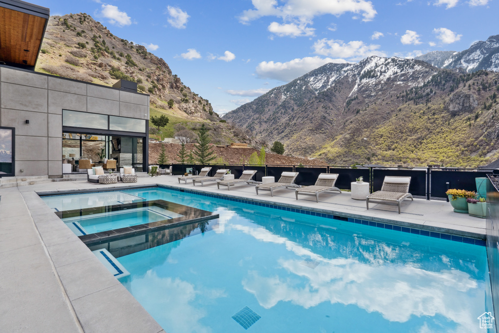 View of swimming pool featuring a patio area, a mountain view, and an in ground hot tub