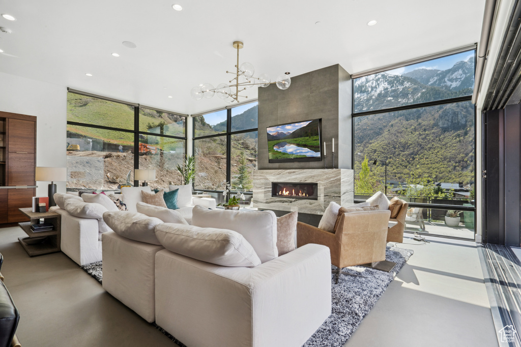 Living room with a mountain view, expansive windows, a tiled fireplace, and a chandelier