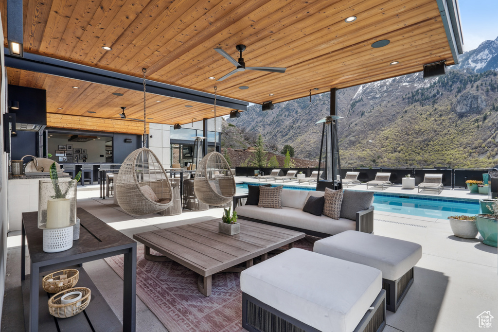 View of terrace with a mountain view, outdoor lounge area, ceiling fan, and a fenced in pool