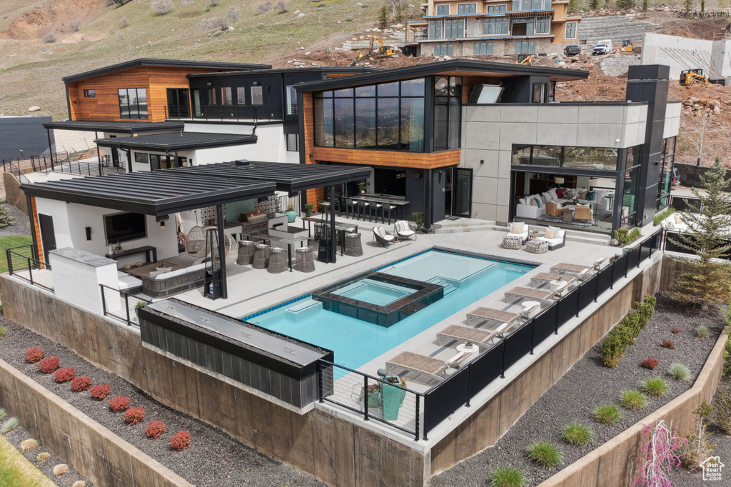 Back of house featuring a patio, a balcony, and an in ground hot tub