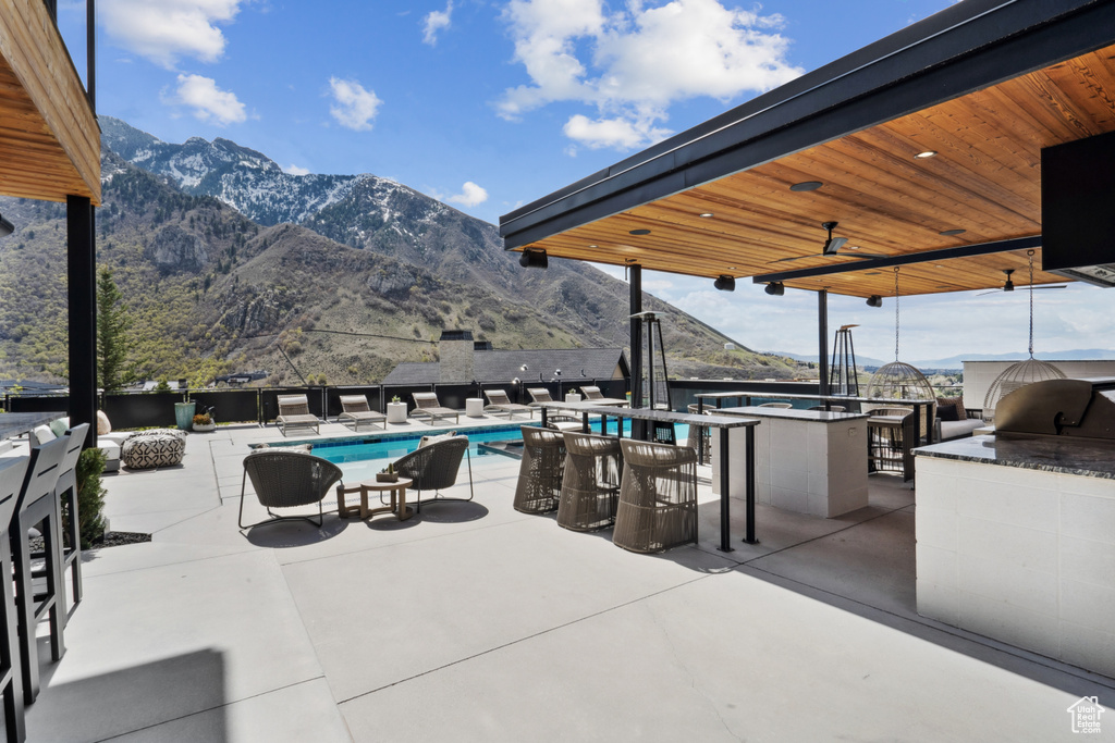View of patio / terrace with a fenced in pool, a mountain view, ceiling fan, and exterior bar