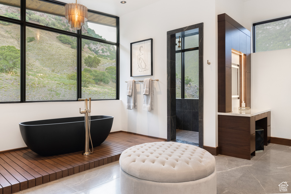 Bathroom featuring vanity, an inviting chandelier, tile flooring, and a bath