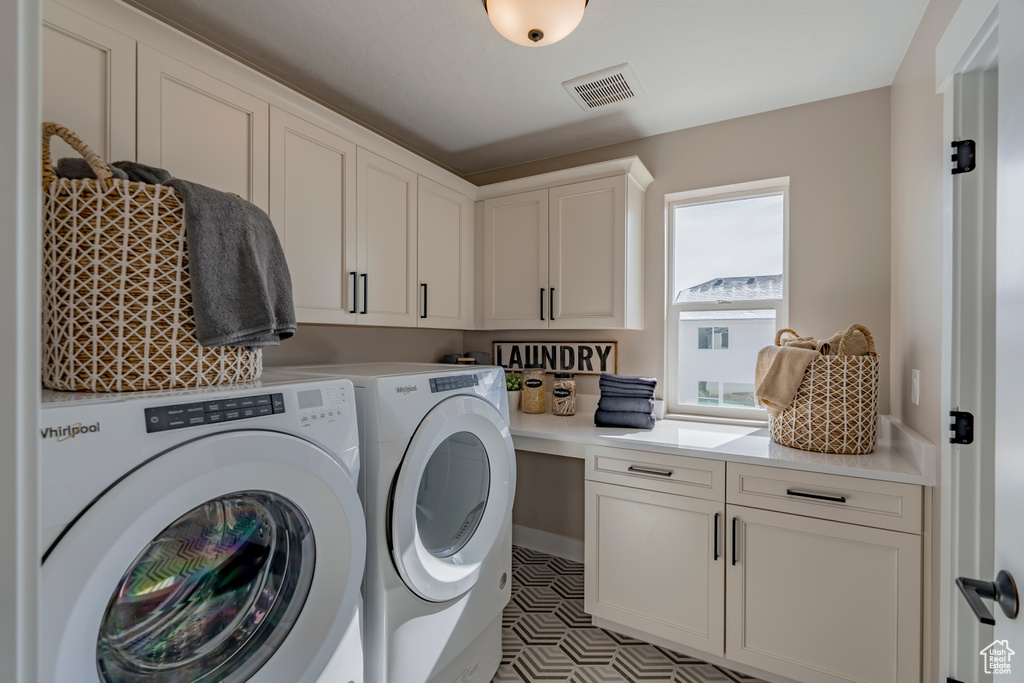 Laundry room featuring washer and clothes dryer, cabinets, and light tile flooring