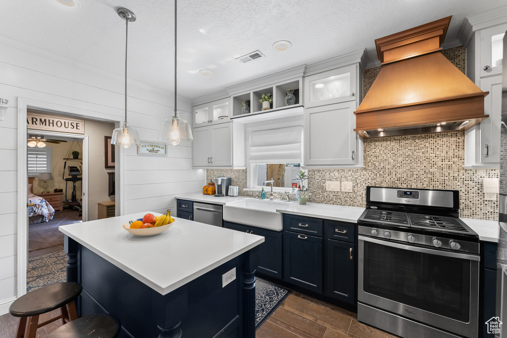 Kitchen featuring appliances with stainless steel finishes, a center island, custom exhaust hood, white cabinets, and sink