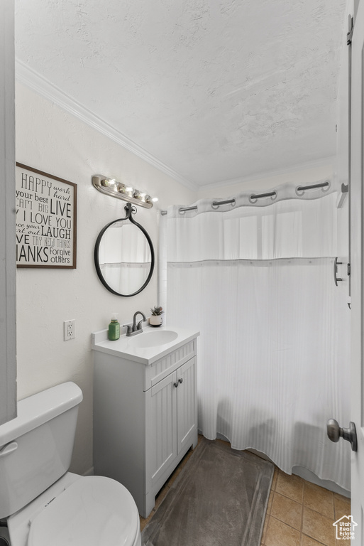 Bathroom featuring tile floors, vanity with extensive cabinet space, toilet, and crown molding
