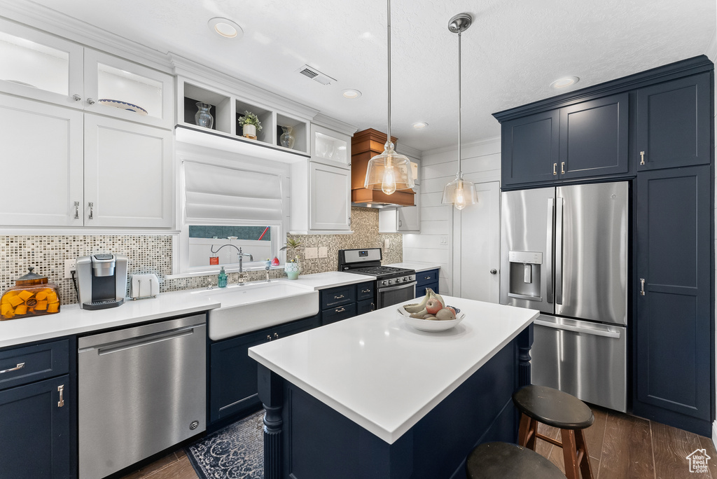 Kitchen featuring backsplash, appliances with stainless steel finishes, a center island, and sink
