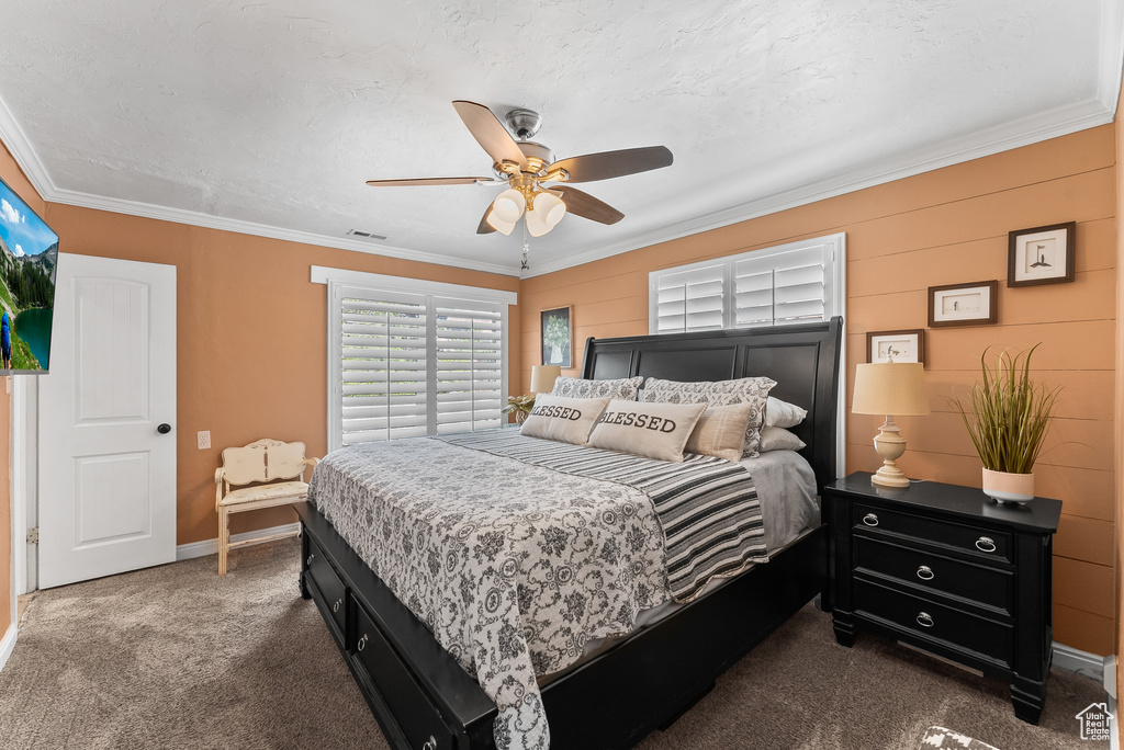 Bedroom featuring dark colored carpet, crown molding, and ceiling fan