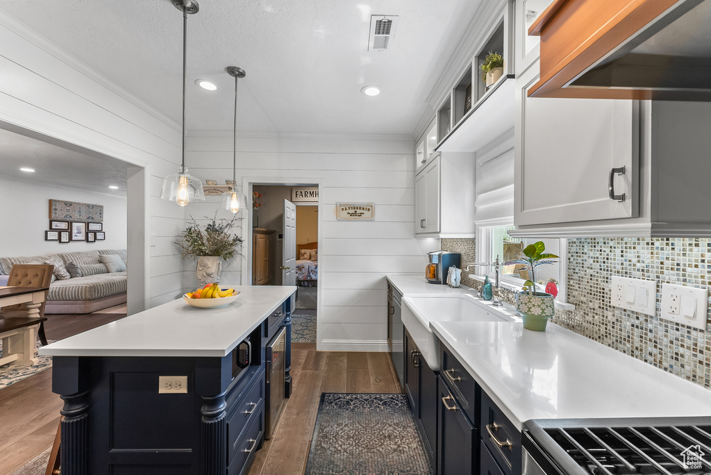 Kitchen featuring dark hardwood / wood-style flooring, hanging light fixtures, white cabinetry, and tasteful backsplash