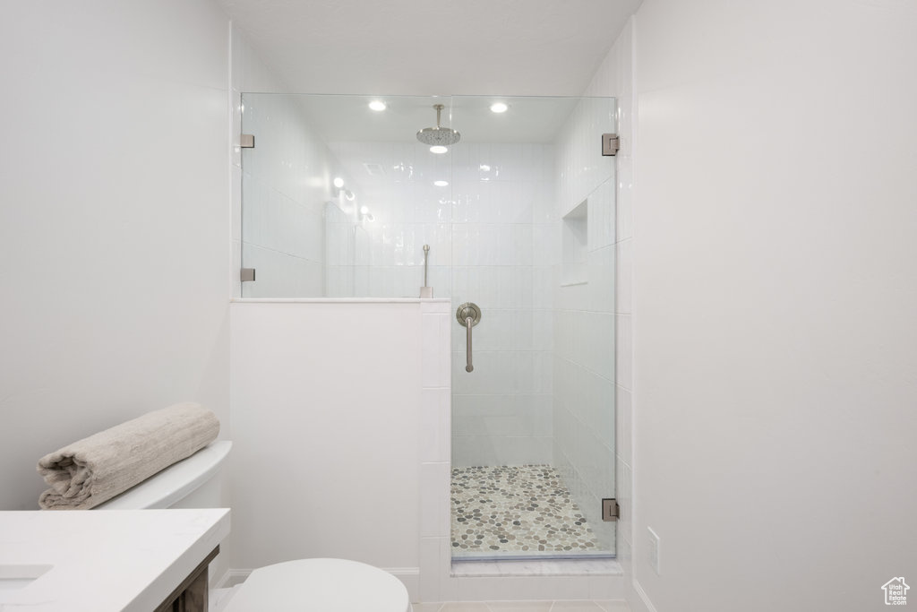 Bathroom with vanity, a shower with shower door, and toilet