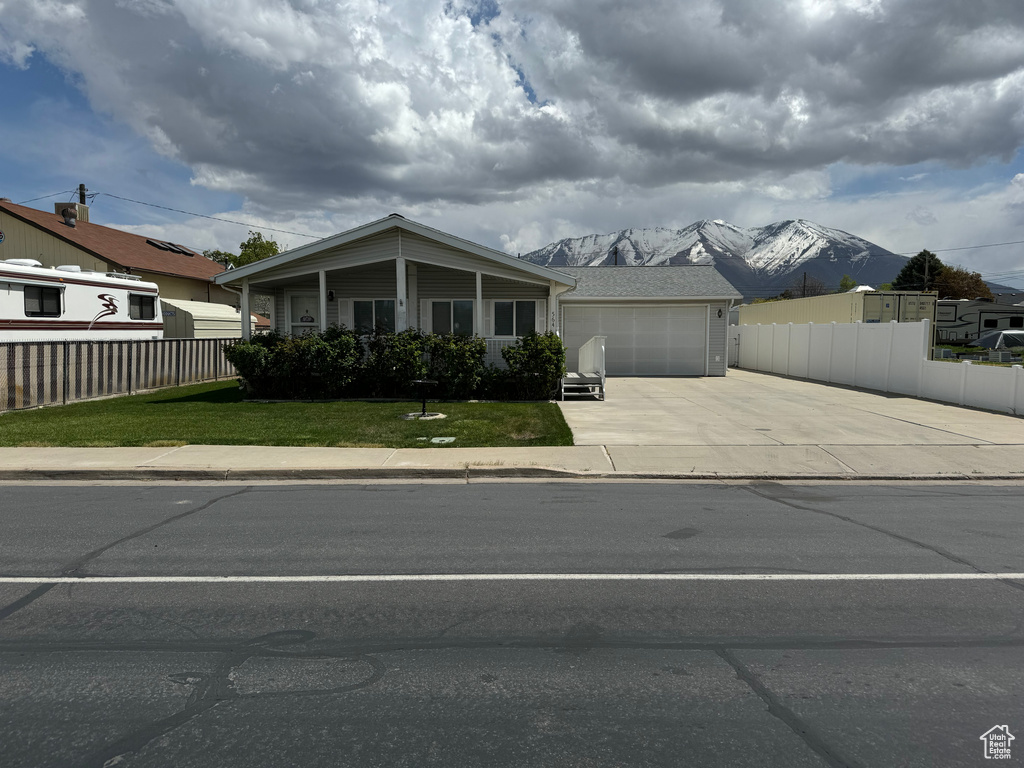 View of front facade with a front yard, a mountain view, and a garage