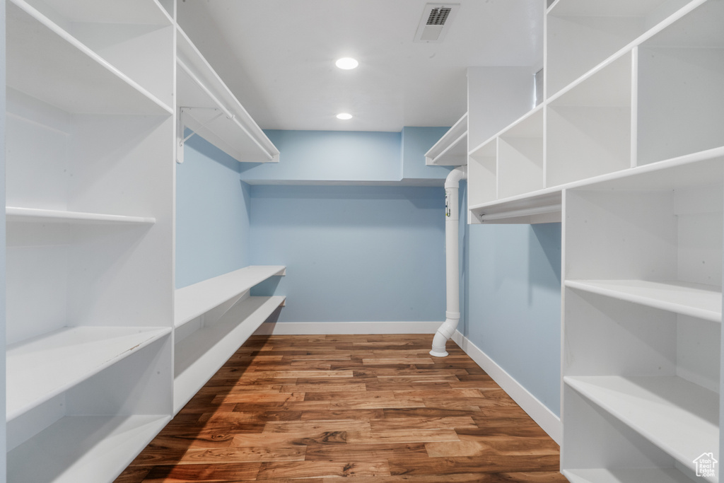 Walk in closet with hardwood / wood-style flooring