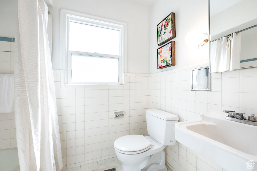 Full bathroom with tile walls, shower / tub combo with curtain, tile flooring, sink, and toilet