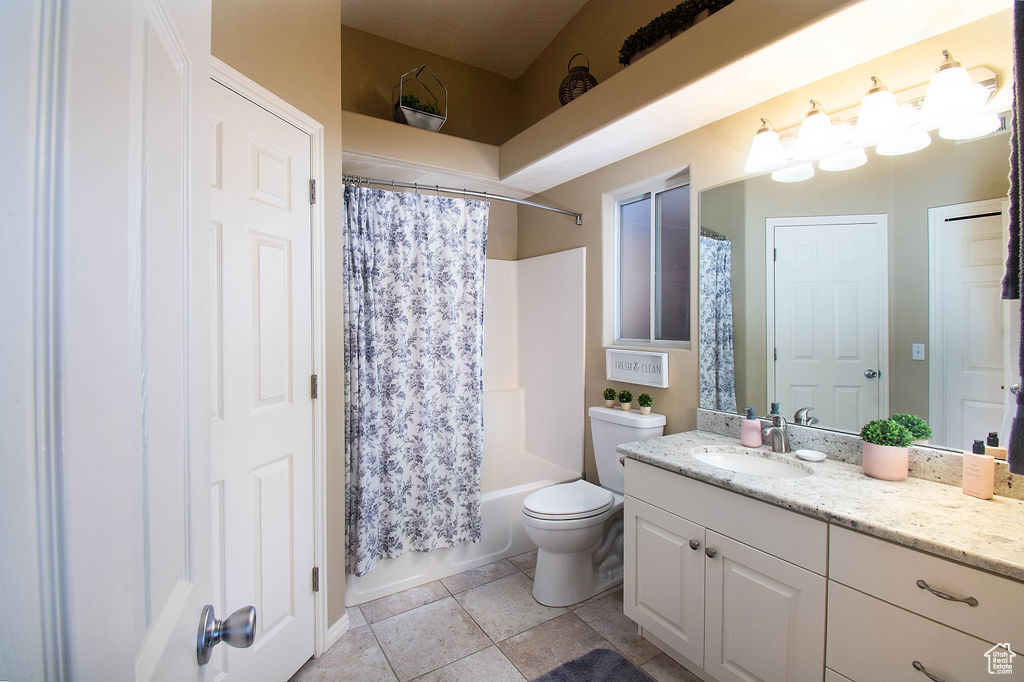 Full bathroom with shower / tub combo, vanity with extensive cabinet space, toilet, and tile floors