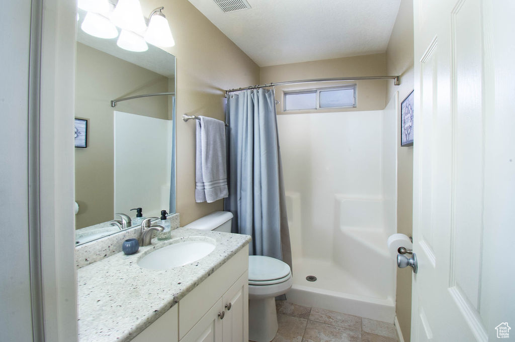 Bathroom featuring a shower with curtain, large vanity, toilet, and tile flooring