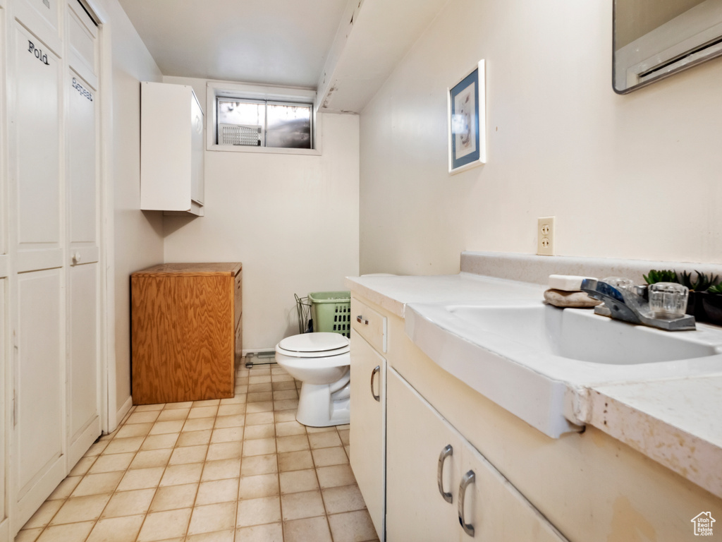 Bathroom with tile floors, a wall unit AC, vanity, and toilet