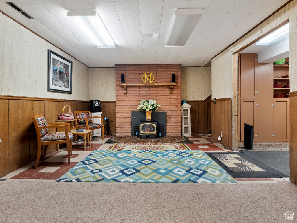 Living area with a wood stove, carpet floors, and brick wall