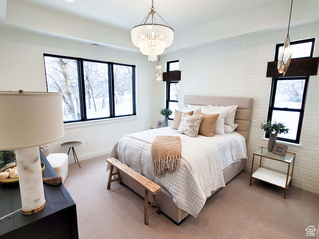 Carpeted bedroom with brick wall and a chandelier