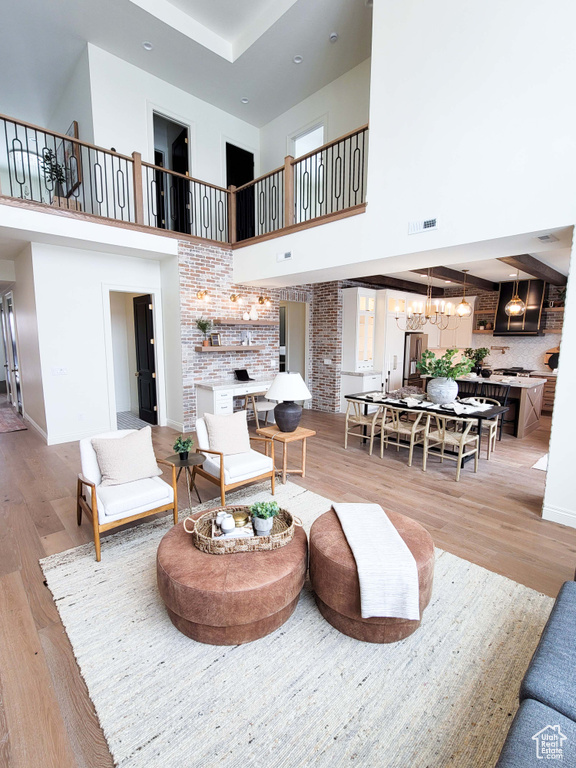 Living room featuring a towering ceiling, a chandelier, and light wood-type flooring