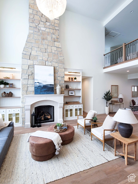 Living room featuring a towering ceiling, a large fireplace, and wood-type flooring