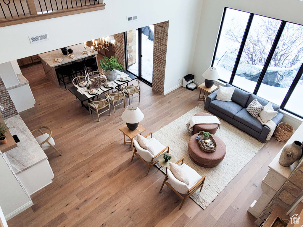 Living room with light hardwood / wood-style floors, a chandelier, and a towering ceiling