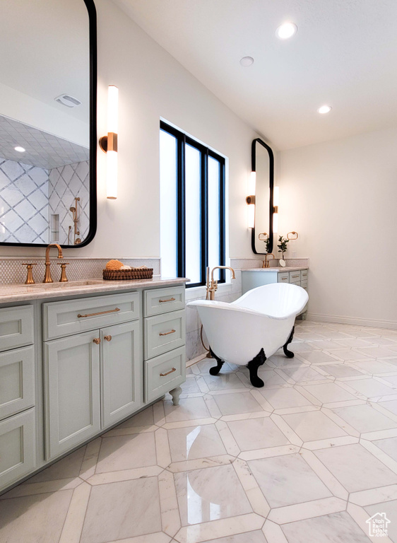 Bathroom with vanity, a bathtub, and decorative backsplash