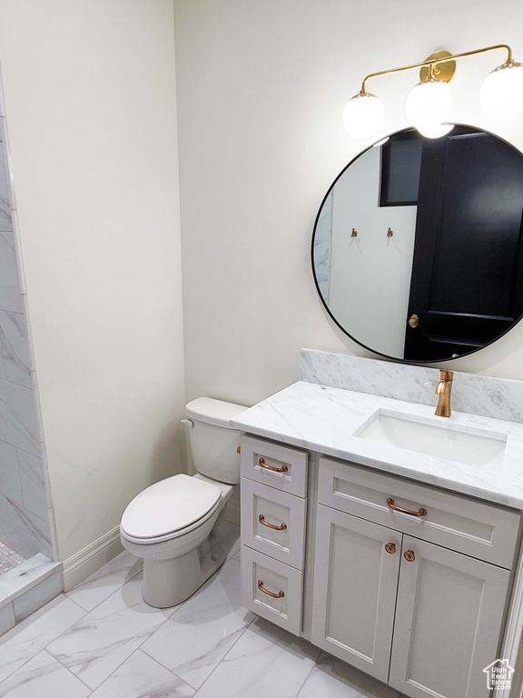 Bathroom featuring toilet, walk in shower, and vanity