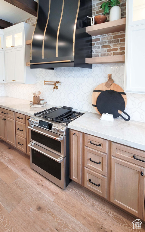 Kitchen with white cabinets, light wood-type flooring, and double oven range