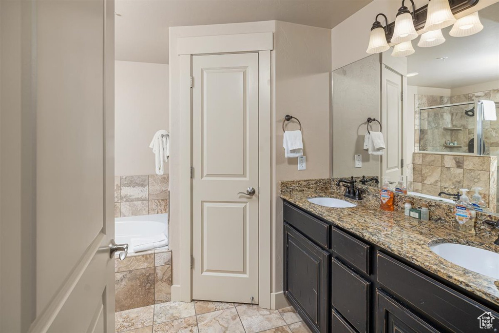 Bathroom featuring independent shower and bath, tile floors, vanity with extensive cabinet space, and dual sinks