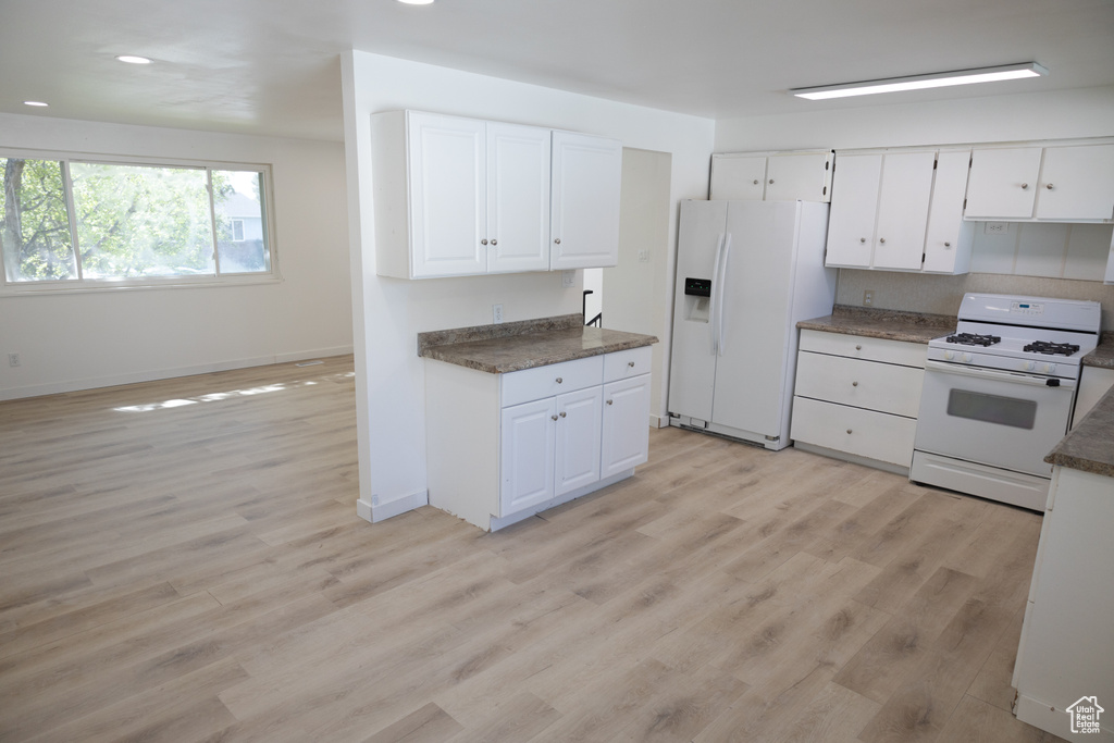 Kitchen featuring white appliances, light hardwood / wood-style floors, and white cabinetry