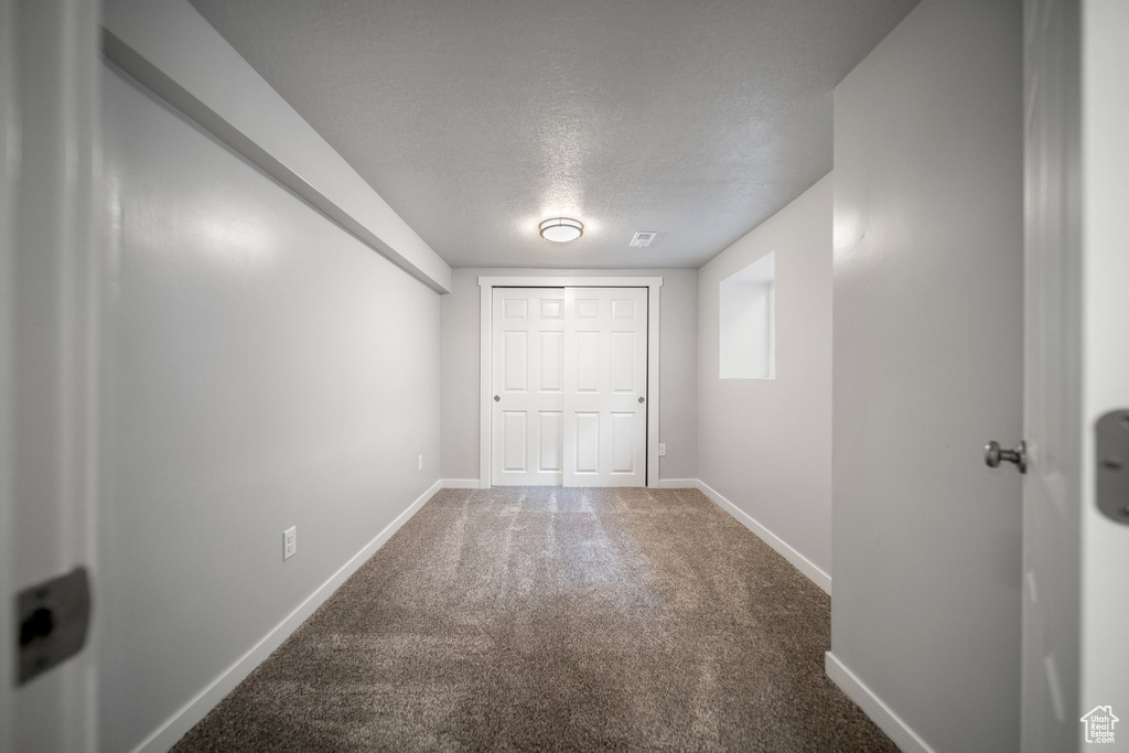 Empty room featuring carpet and a textured ceiling