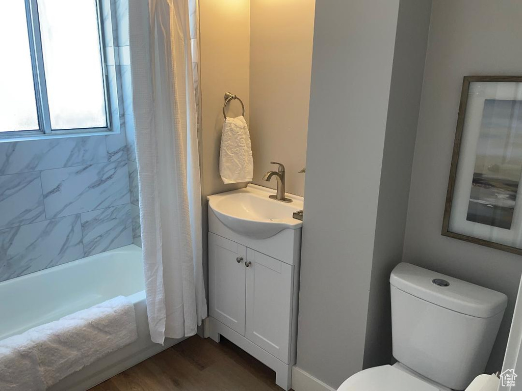 Full bathroom with wood-type flooring, shower / tub combo, vanity, and toilet