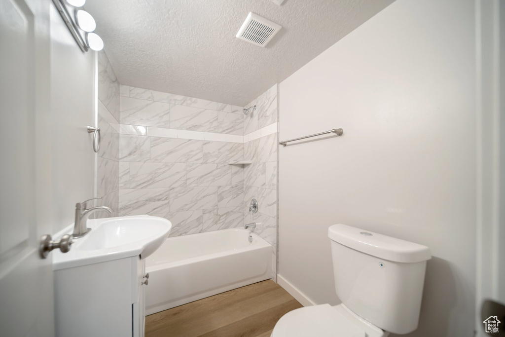 Full bathroom featuring hardwood / wood-style flooring, toilet, vanity, and a textured ceiling