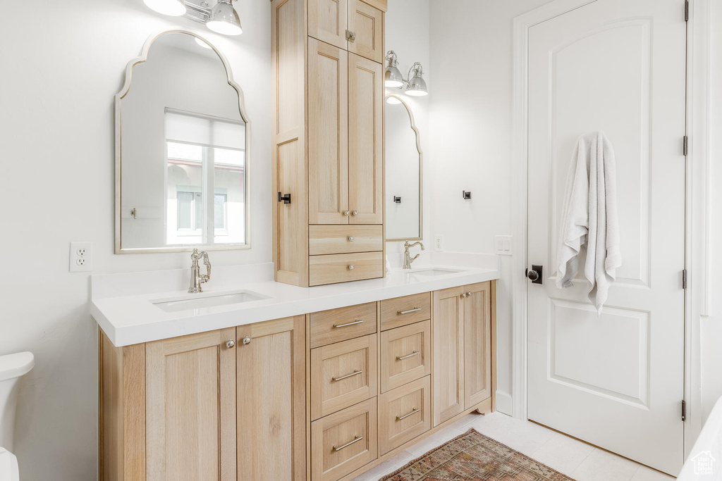 Bathroom featuring tile flooring, dual sinks, toilet, and large vanity