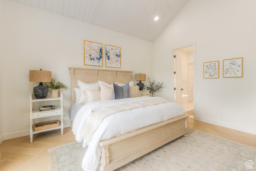 Bedroom featuring ensuite bath, light parquet floors, and high vaulted ceiling