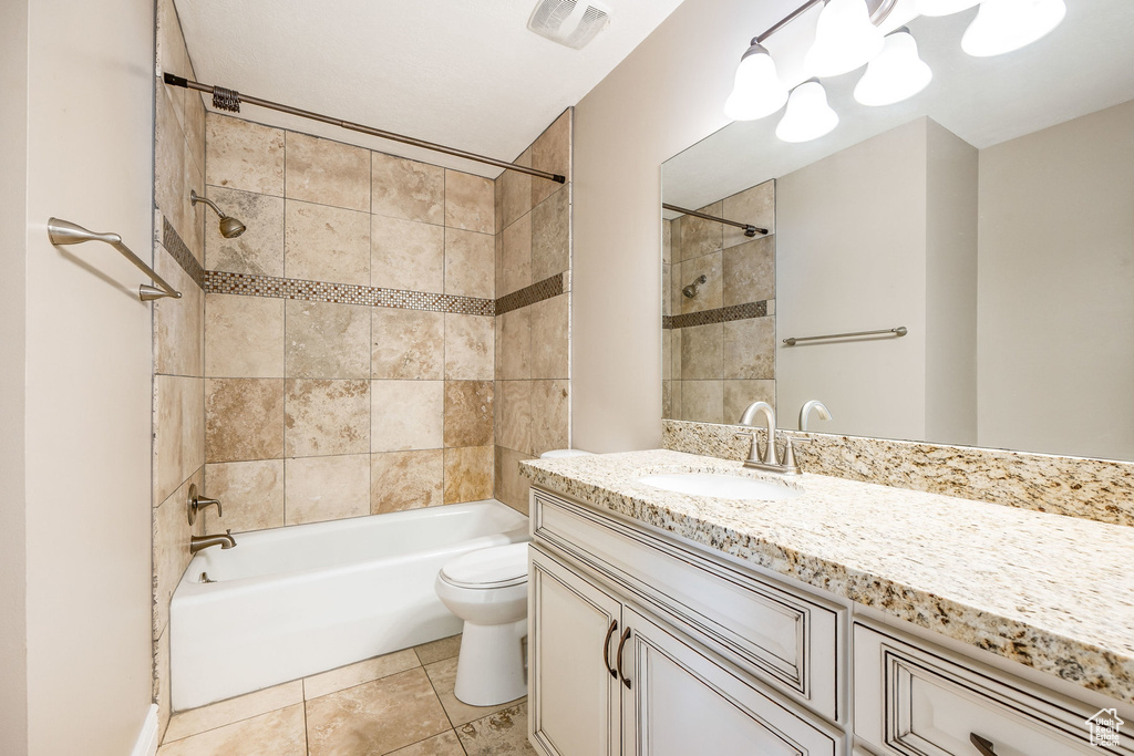 Full bathroom featuring oversized vanity, toilet, tiled shower / bath, and tile flooring
