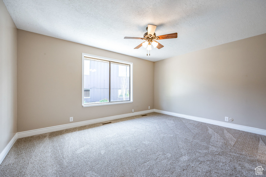 Empty room with a textured ceiling, ceiling fan, and carpet
