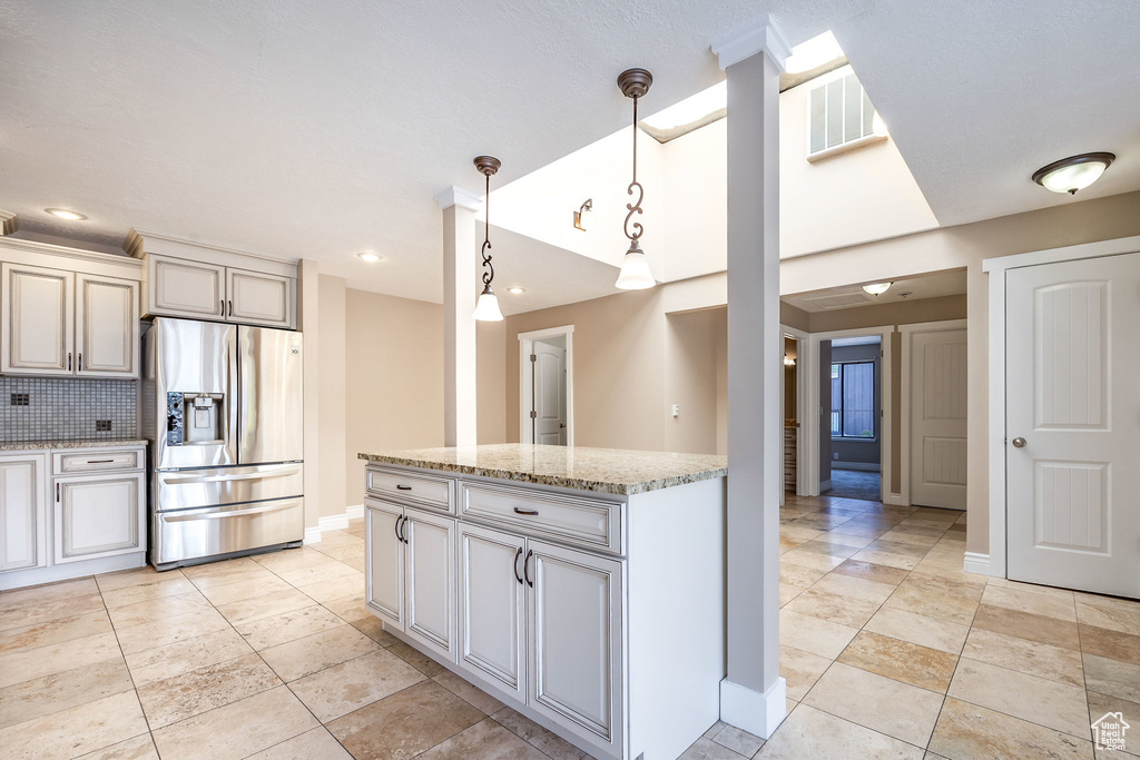 Kitchen featuring hanging light fixtures, light tile floors, and stainless steel refrigerator with ice dispenser
