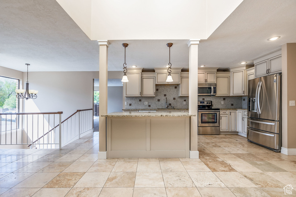 Kitchen featuring backsplash, pendant lighting, stainless steel appliances, and light stone countertops