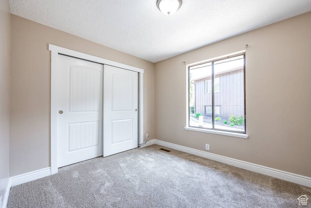 Unfurnished bedroom with a closet, multiple windows, and carpet