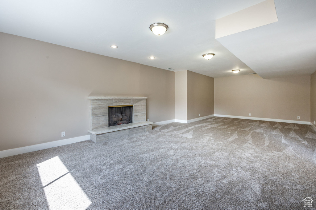 Unfurnished living room featuring a fireplace and carpet floors