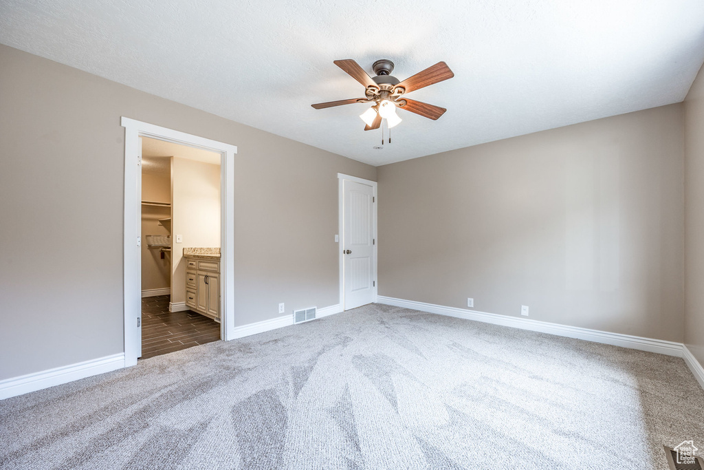 Unfurnished bedroom with ensuite bath, ceiling fan, and carpet floors