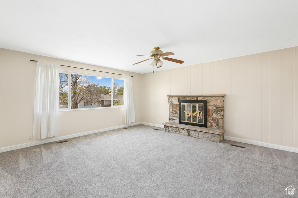 Unfurnished living room with ceiling fan, a fireplace, and carpet floors