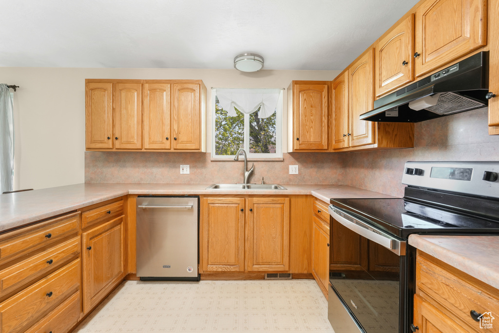 Kitchen featuring appliances with stainless steel finishes, sink, tasteful backsplash, and light tile floors