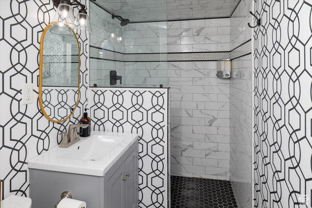 Bathroom featuring oversized vanity, tasteful backsplash, and a tile shower