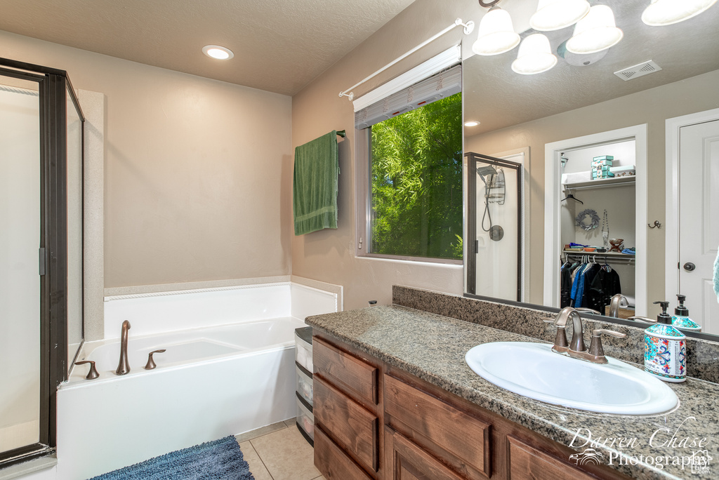 Bathroom featuring oversized vanity, separate shower and tub, tile floors, and a textured ceiling