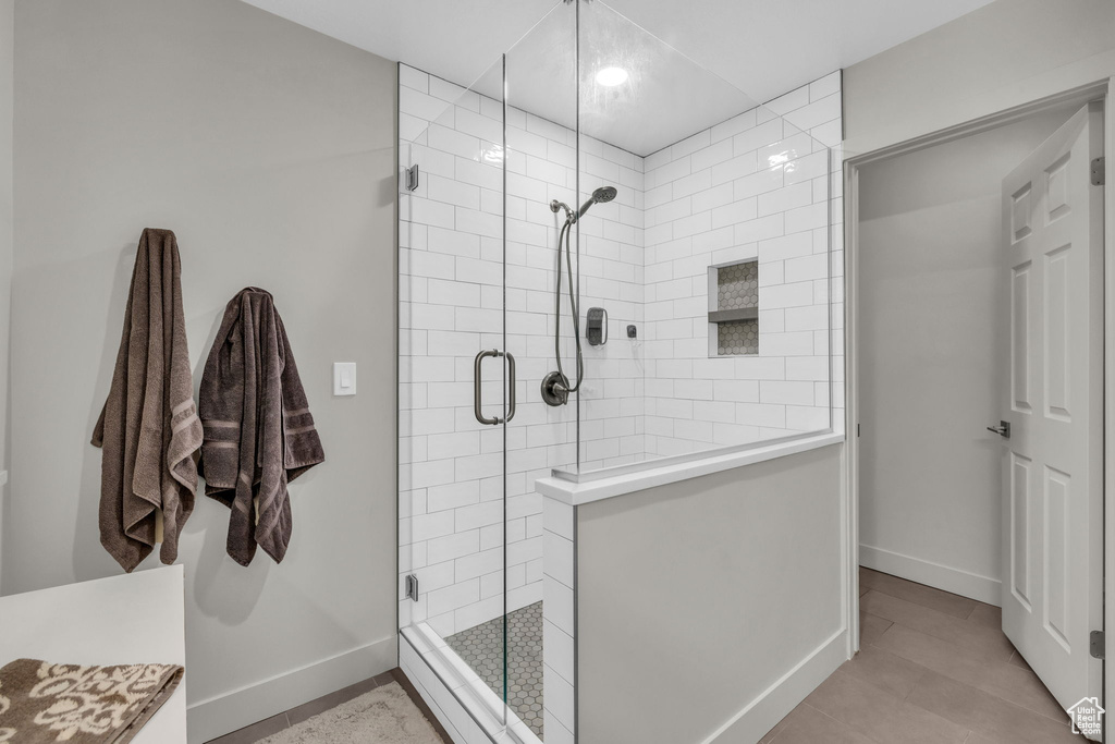 Bathroom with a shower with shower door, vanity, and tile flooring