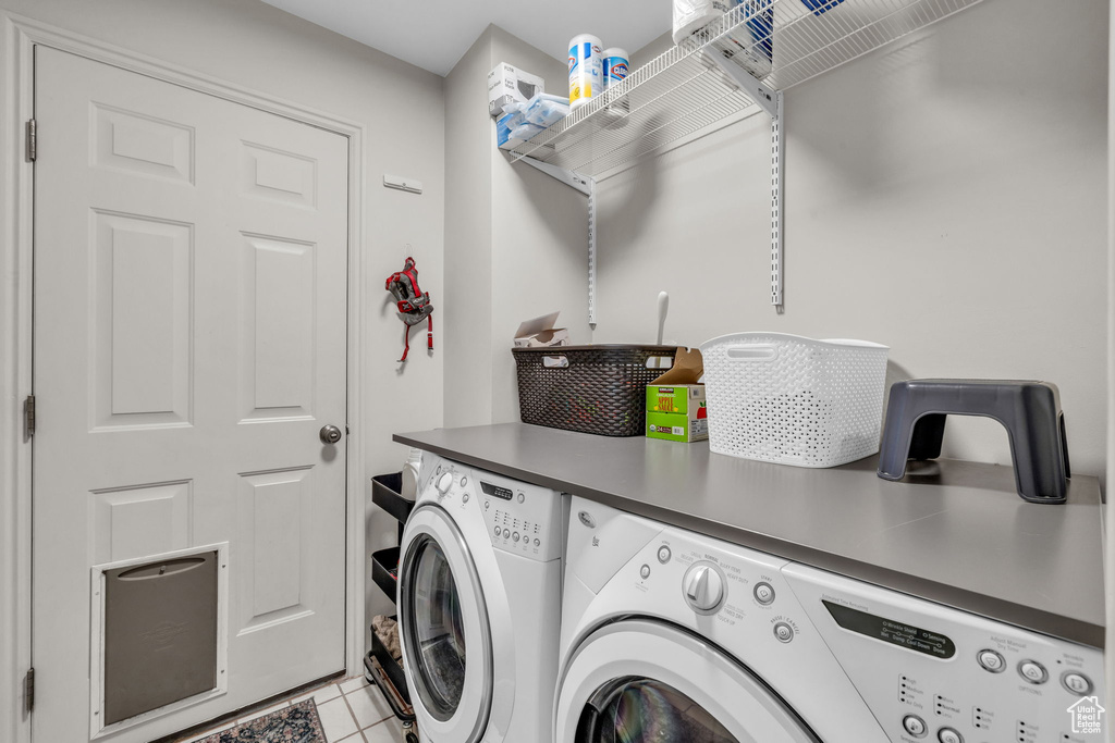 Laundry room with light tile floors and washer and clothes dryer