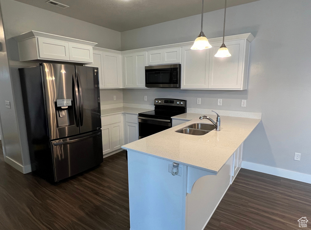 Kitchen featuring white cabinets, dark hardwood / wood-style floors, kitchen peninsula, stainless steel appliances, and sink